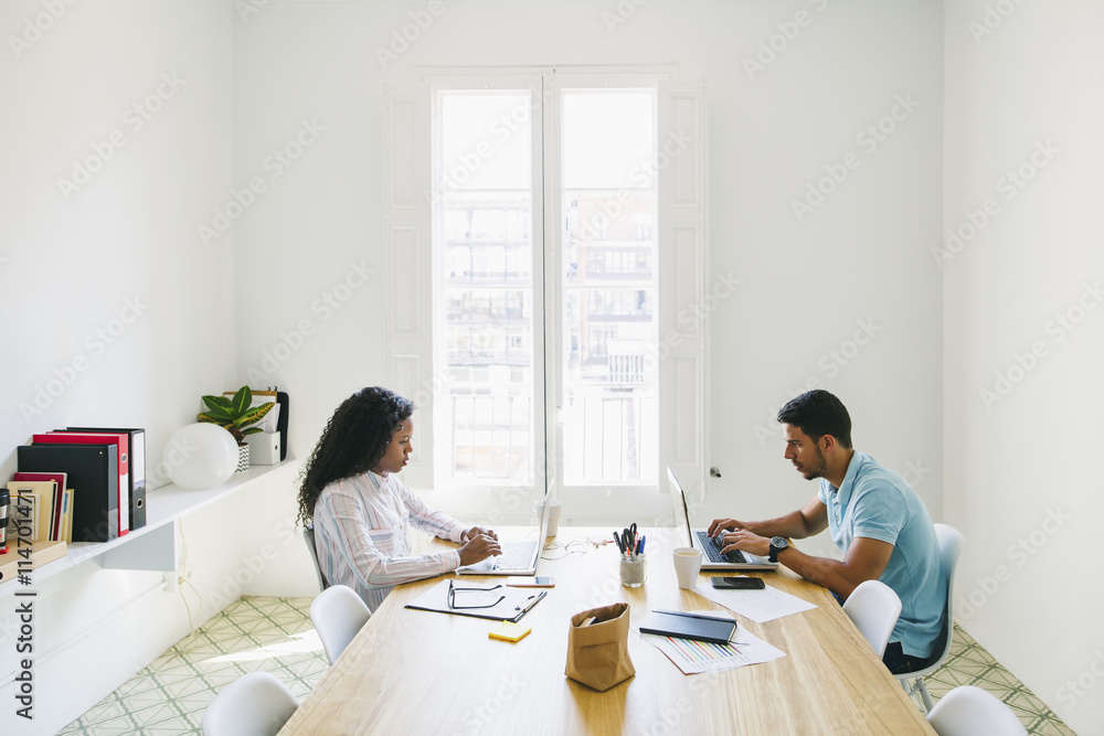 Young businessman and woman working together in office, using laptop Young businessman and woman working together in office, using laptop