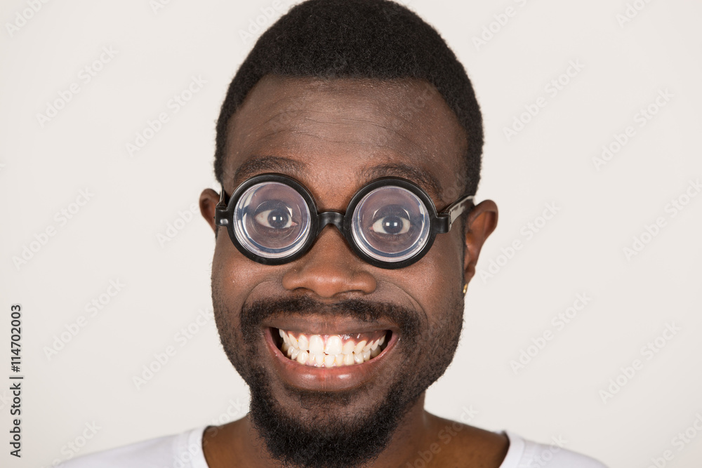 junger Mann mit dunkler Hautfarbe hat Spaß und zieht Grimasse mit Brille junger Mann mit dunkler Hautfarbe hat Spaß und zieht Grimasse mit Brille