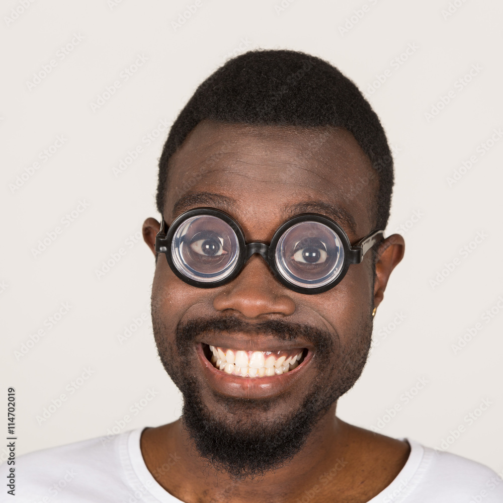 junger Mann mit dunkler Hautfarbe hat Spaß und zieht Grimasse mit Brille junger Mann mit dunkler Hautfarbe hat Spaß und zieht Grimasse mit Brille