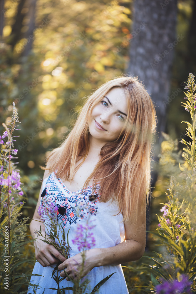 Young beautiful redhead woman in the summer sunset forest Young beautiful redhead woman in the summer sunset forest