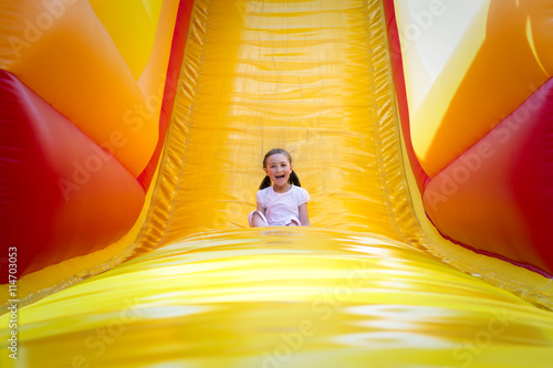 фотографія Happy little girl having lots of fun on a jumping castle while sliding