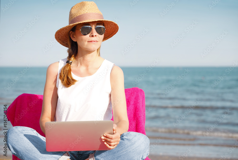 Woman working on laptop on the beach Woman working on laptop on the beach