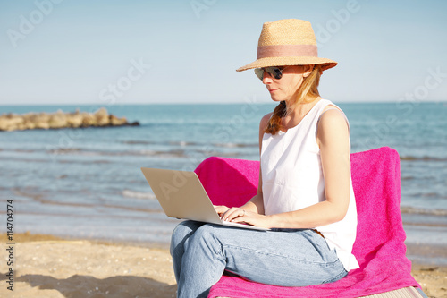 Woman working on laptop on the beach © sepy
