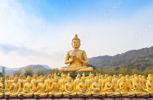 big golden buddha statue and many small golden buddha statues sitting in row in temple nakornnayok thailand.