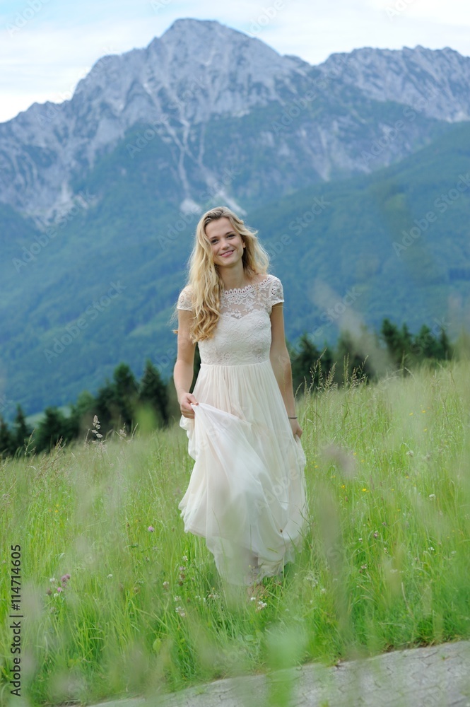 Junge Frau läuft in einem langen Kleid über eine Bergwiese im Berchtesgadener Land