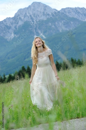 Junge Frau läuft in einem langen Kleid über eine Bergwiese im Berchtesgadener Land