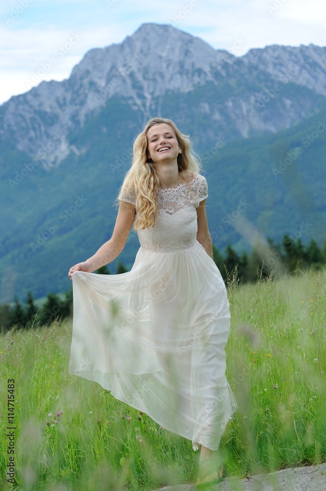 Junge Frau läuft in einem langen Kleid über eine Bergwiese im Berchtesgadener Land