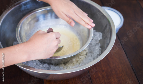 Children hand making home made ice cream with iced bowl. Spinning steel bowl for making Vanilla Ice Cream.