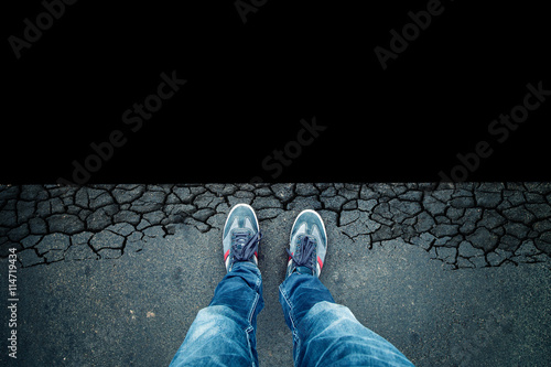 Top view of a man standing in front of the dangerous black abyss background. Point of view perspective used. photo