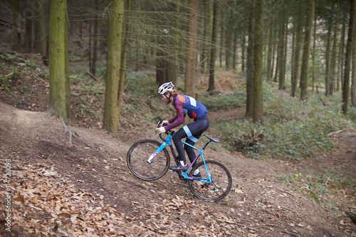 Cross-country cyclist ascending a slope in a forest