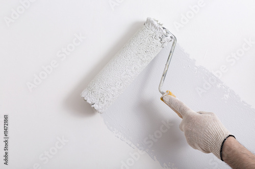 Close up of painter hand painting a wall grey with paint roller