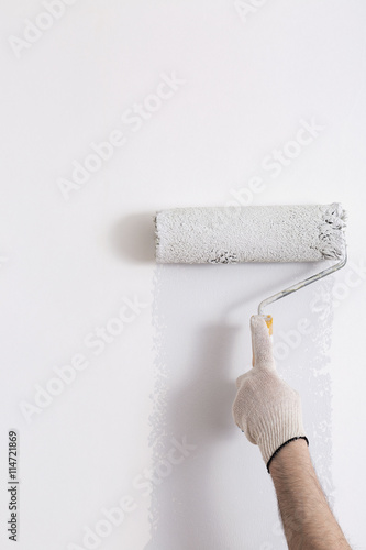 Close up of painter hand painting a wall grey with paint roller