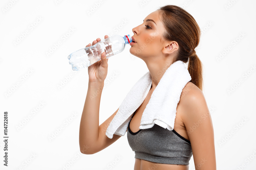 Portrait of young beautiful sportive girl over white background. Drinking water Portrait of young beautiful sportive girl over white background. Drinking water