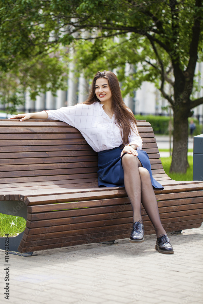 Young beautiful girl sitting on a bench in the summer park Young beautiful girl sitting on a bench in the summer park