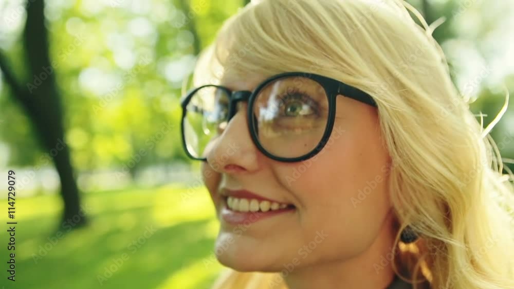 Face of happy blonde with glasses in a summer park. Slow motion. Face of happy blonde with glasses in a summer park. Slow motion.
