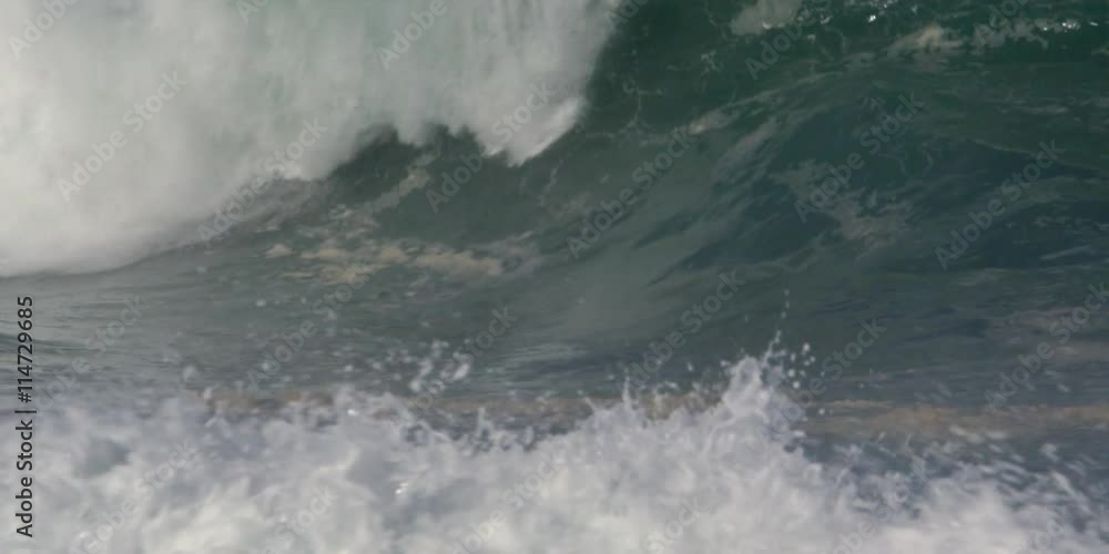 White foam churning in the foreground as sand-laden green waves curl and plunge White foam churning in the foreground as sand-laden green waves curl and plunge