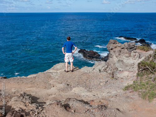 man views ocean from cliff