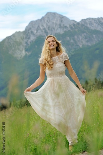 Junge Frau im langen Sommerkleid auf einer Bergwiese vor dem Hochstaufen im Berchtesgadener Land