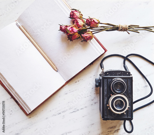 Vintage camera on marble background with blank notebook and drie photo