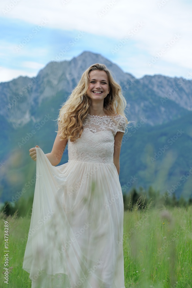 Junge Frau im langen Sommerkleid auf einer Bergwiese vor dem Hochstaufen im Berchtesgadener Land