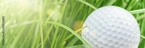 Golf ball over green grass background. Sport and leisure concept 
