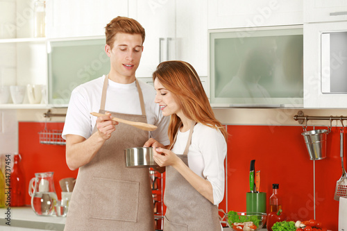 Couple in aprons cooking in...