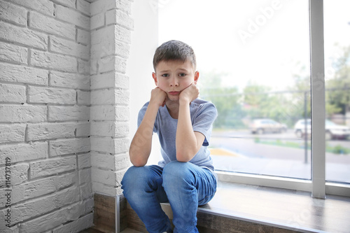 Sad boy sitting near window