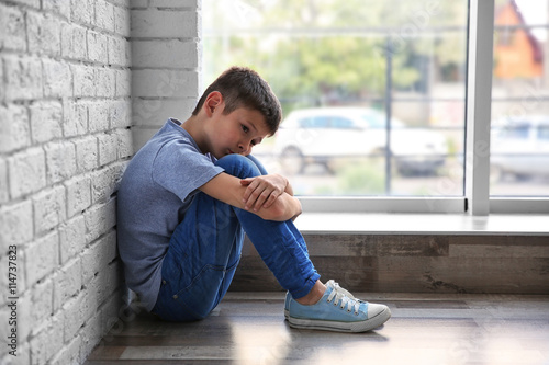 Sad boy sitting near window