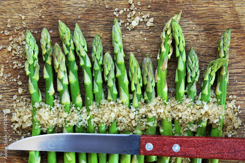 Asparagus with knife and sea salt on cutting board