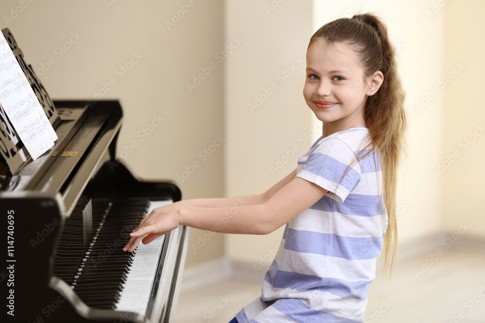 Fototapeta Small girl playing piano