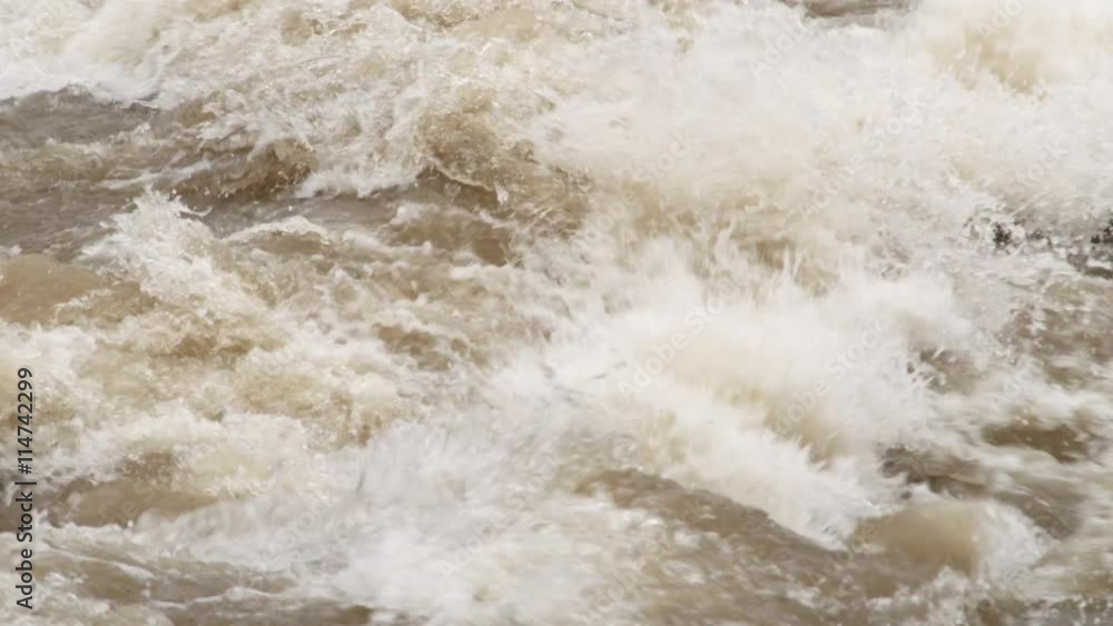 Close-up churning rapids on a muddy river in flood Close-up churning rapids on a muddy river in flood