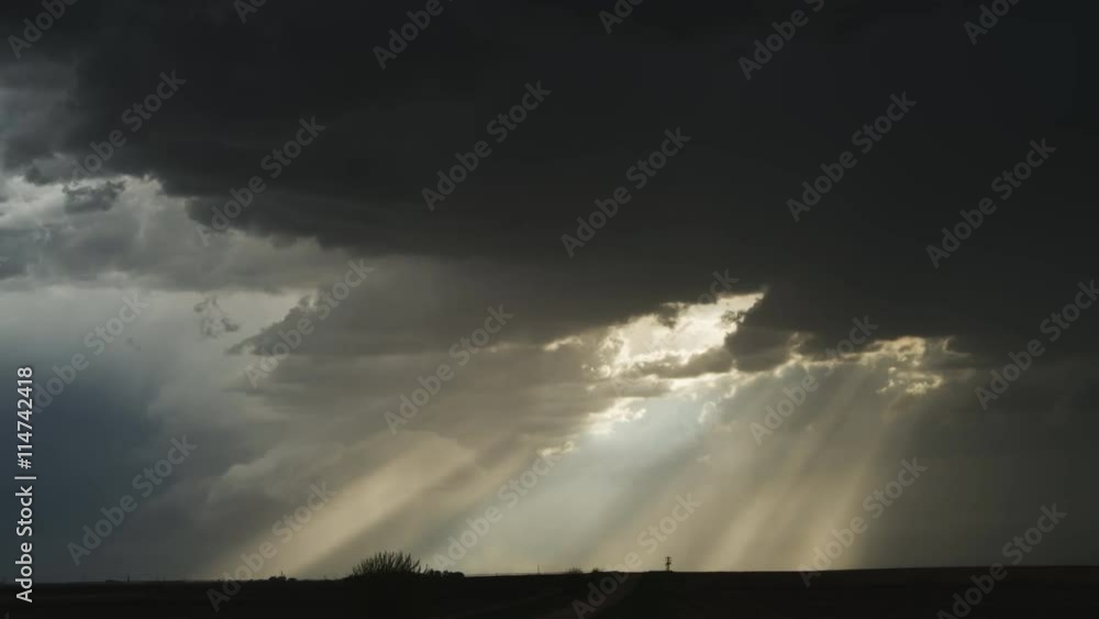 Time-lapse dark cloud and sun rays moving to the right across the prairie at dusk Time-lapse dark cloud and sun rays moving to the right across the prairie at dusk