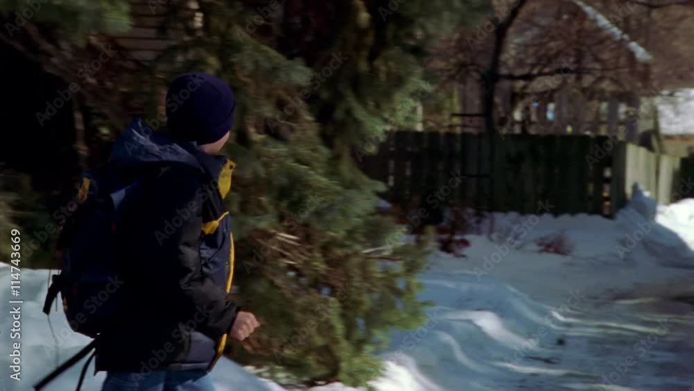 Boy walking through a suburban neighborhood in winter Boy walking through a suburban neighborhood in winter