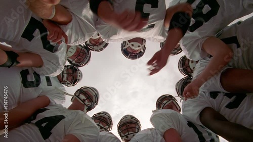 Looking up from ground at center of a football huddle