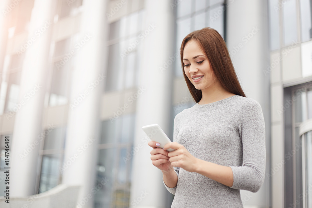 Business woman writing a message on the phone and smiling. Business concept. Business woman writing a message on the phone and smiling. Business concept.