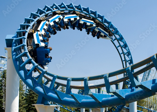Cork-screw Rollercoaster and Ferris-Wheel at amusement park. Slight motion blur on Rollercoaster cars