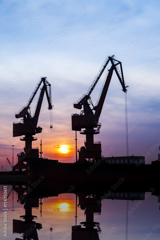 In the evening, the silhouette of port cranes