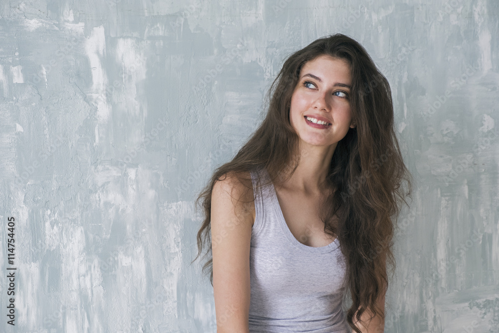 Dreaming brunette smiling up against of textured wall Dreaming brunette smiling up against of textured wall