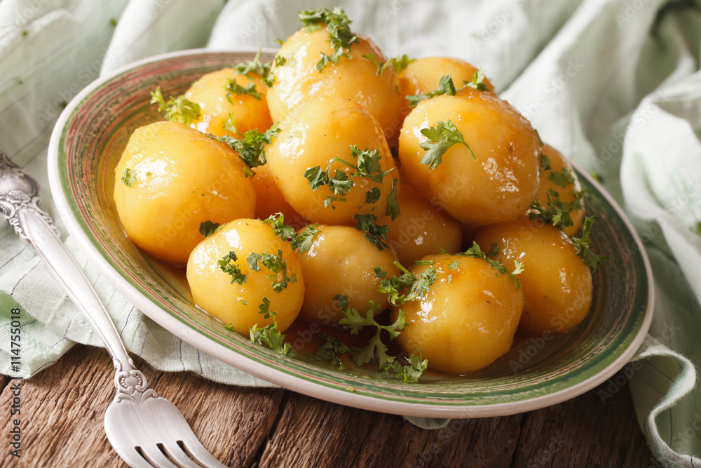 Glazed new potatoes with parsley close-up on the table. Horizontal
Glazed new potatoes with parsley close-up on the table. Horizontal