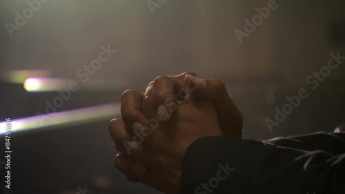 Close-up of praying man's clasped hands and bowed head