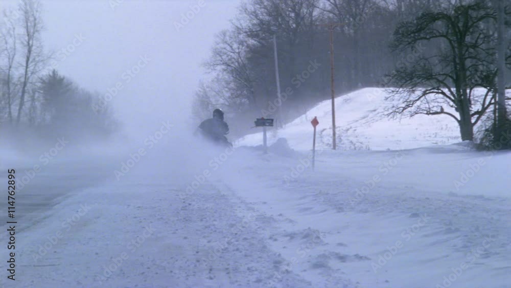 Snowmobilers racing along snow-packed rural highway between drifts Snowmobilers racing along snow-packed rural highway between drifts