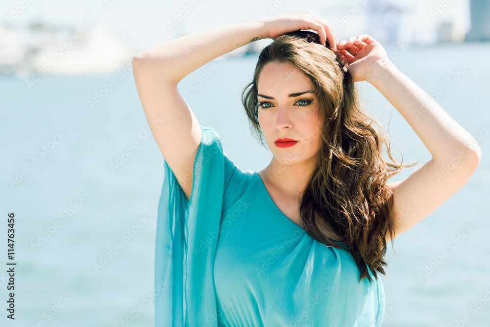 Woman with blue eyes wearing blue dress in the beach.
