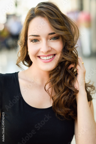 Beautiful young woman with blue eyes smiling in urban background