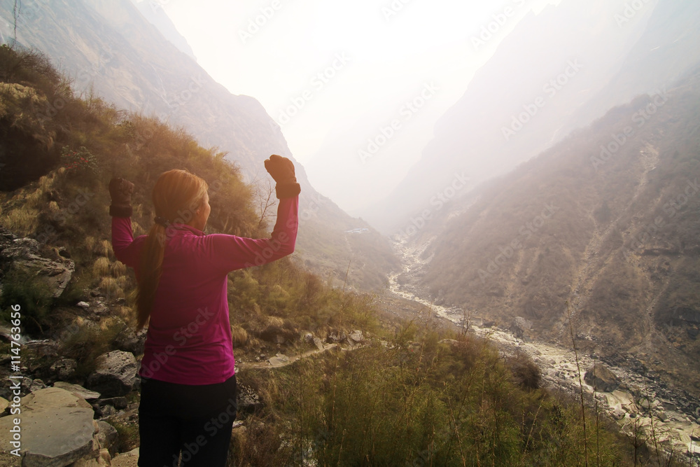 Obraz premium Cheering woman hiker open arms at mountain peak