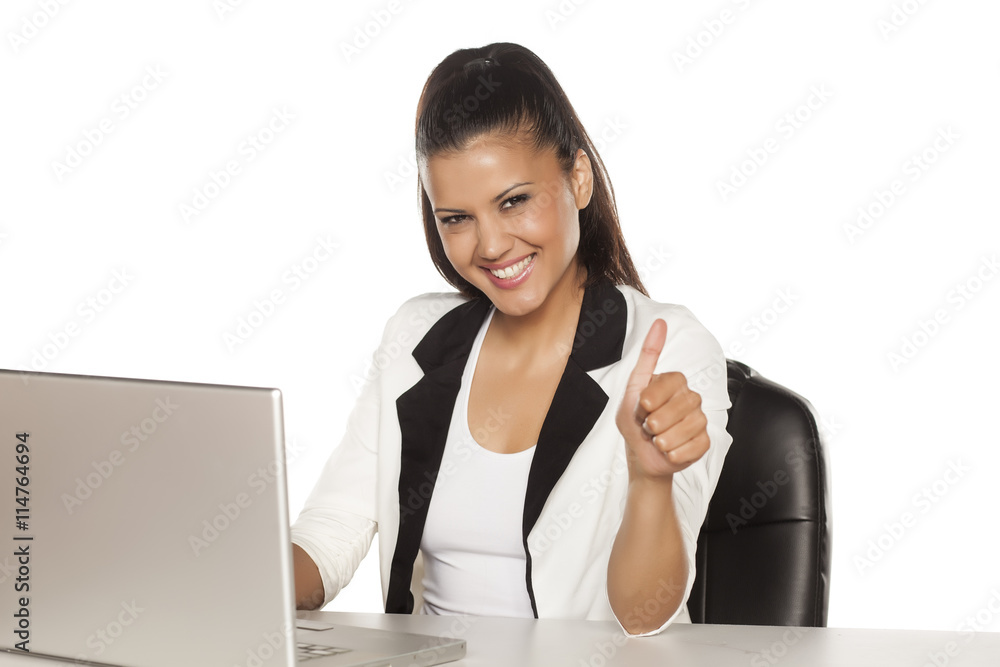 young beautiful latina sitting by laptop and showing thumbs up young beautiful latina sitting by laptop and showing thumbs up