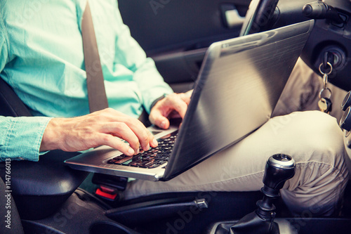 close up of young man with laptop driving car