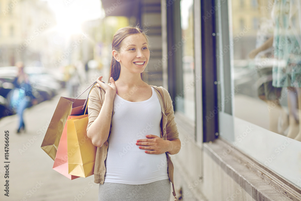 Fototapeta premium happy pregnant woman with shopping bags at city