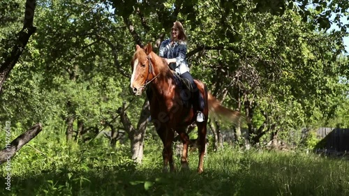 The girl riding a horse in an apple orchard

