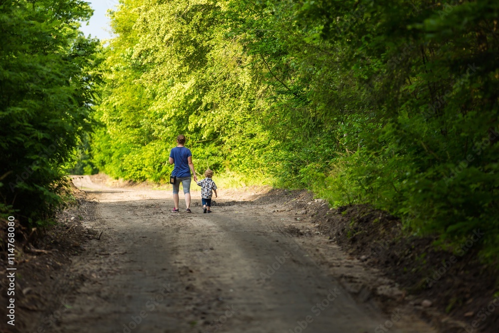 Mother and child walking by forest path Mother and child walking by forest path