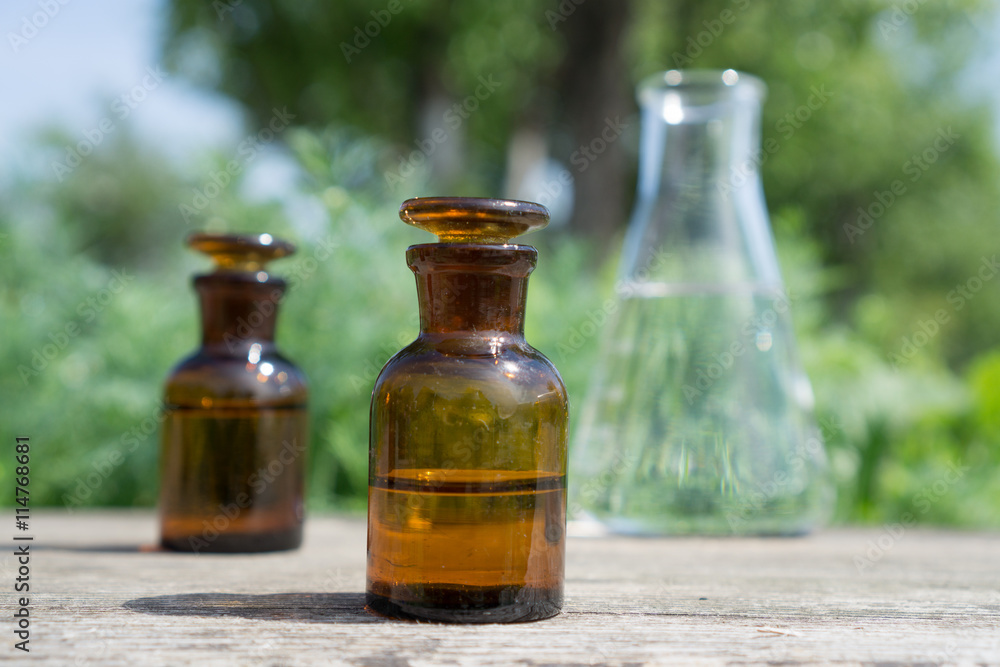 Liquid in chemical ware on a background of plants, fertilizers or pesticides in the garden. Liquid in chemical ware on a background of plants, fertilizers or pesticides in the garden.